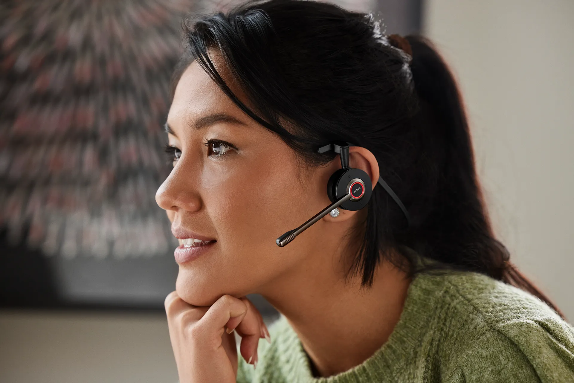 A woman wearing a Jabra Engage 55 Convertible headset with a microphone, engaged in a conversation or virtual meeting